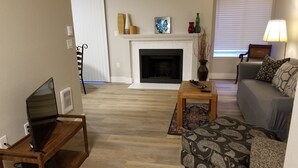 Una sala de estar con chimenea, un sofá, una mesa de centro y un mueble para televisión.
