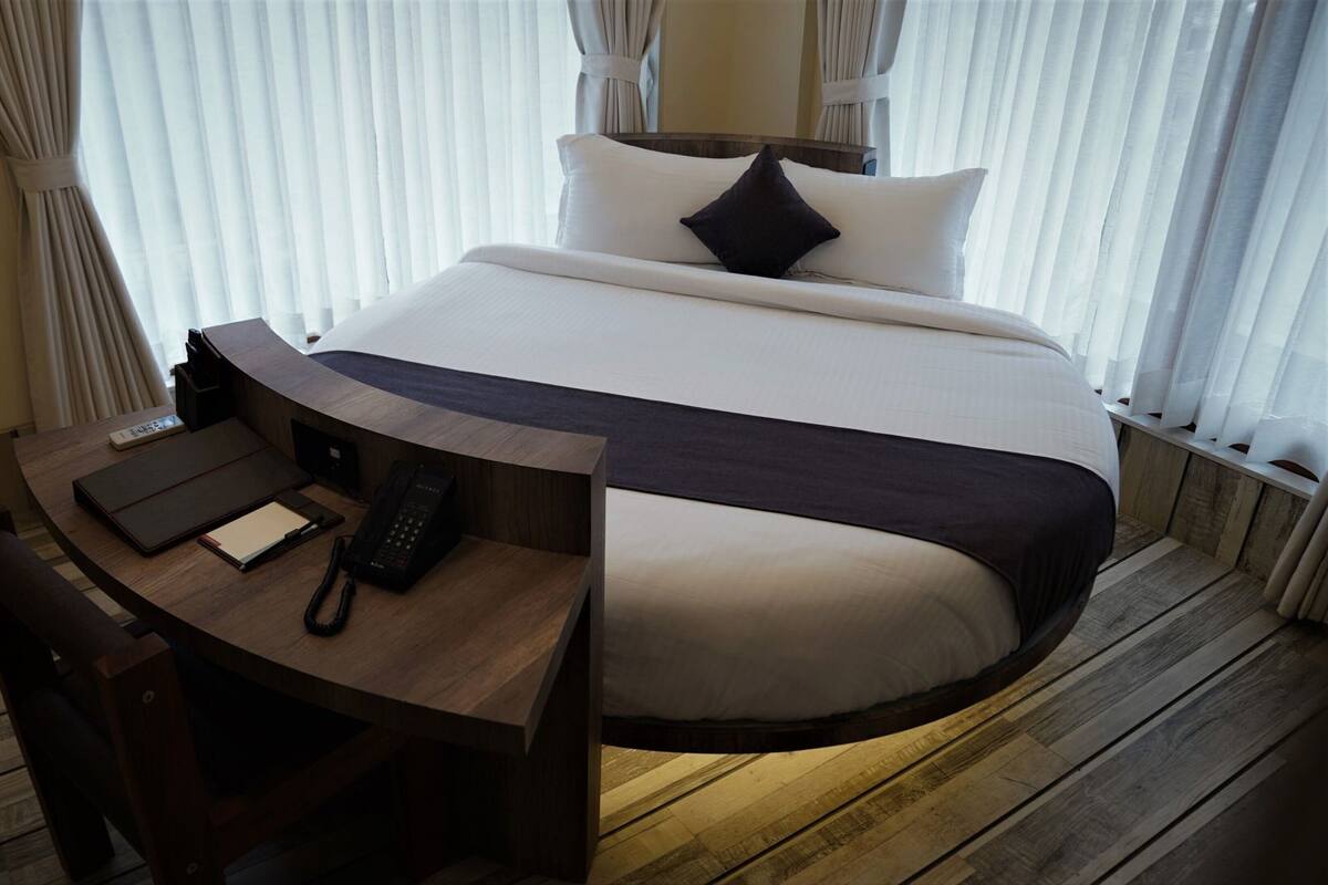 A hotel room with a bed, a desk with a telephone, and a chair.