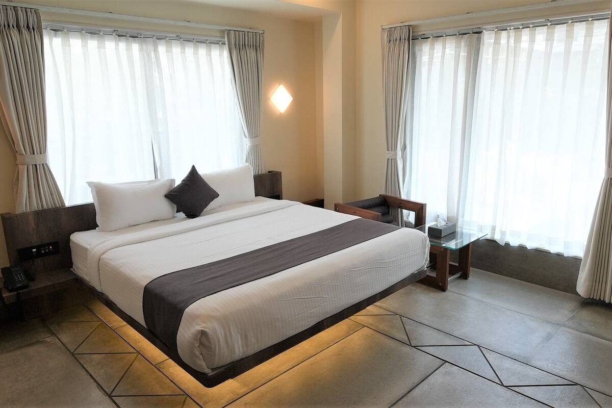 A modern hotel room with a large bed, bedside tables, and a nightstand.