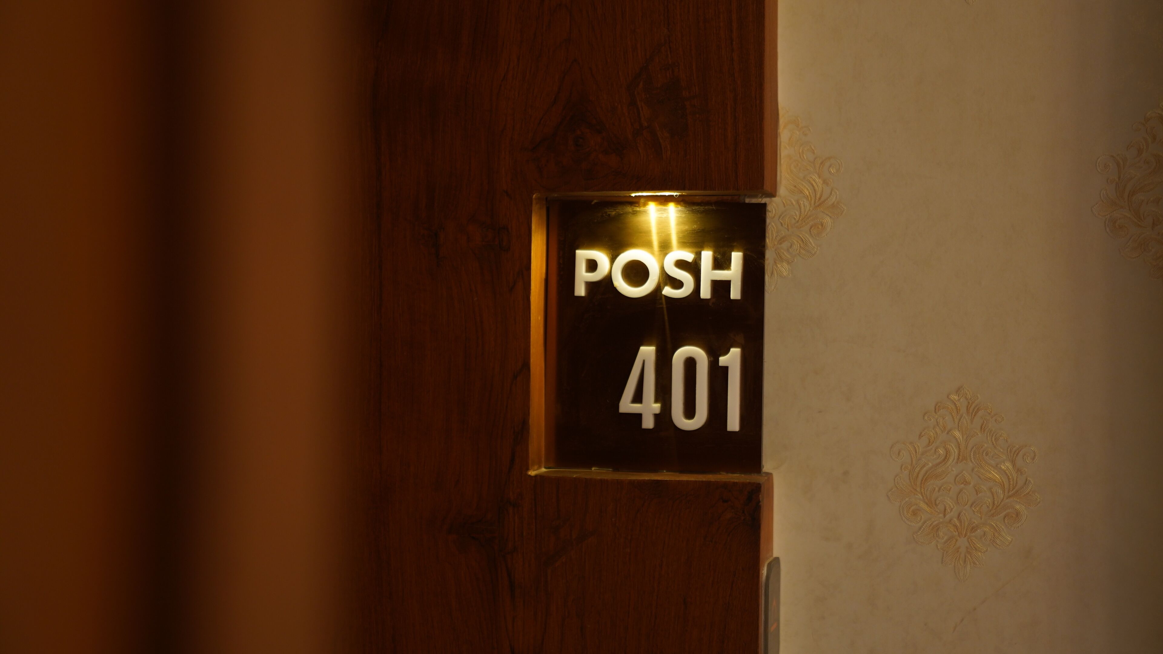 A sign with the text "POSH 401" on a wooden door.