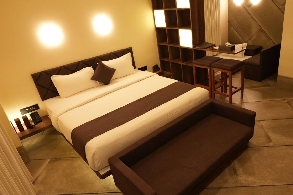 A modern hotel room with a large bed, a desk, and a seating area.