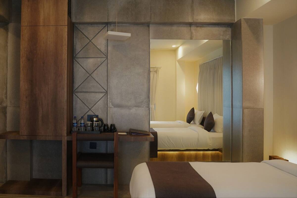A hotel room with a wooden accent wall, a bed, a desk with a chair, and a mirror.