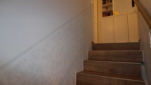 Eine Holztreppe mit einer weißen Wand und einem Bücherregal im Hintergrund.