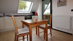 Eine Küche mit Esstisch, Stühlen, einem Fenster und einer Heizung.