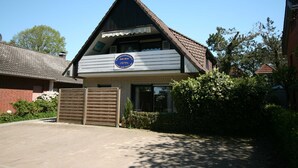 A two-story building with a sloped roof and a sign indicating it is a 'Jade-Blick'. - Ferienwohnungen Jade-blick, WH EG Rechts (Varel)