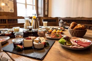 Un buffet de petit-déjeuner proposant une variété de fromages, de charcuteries et de pains.