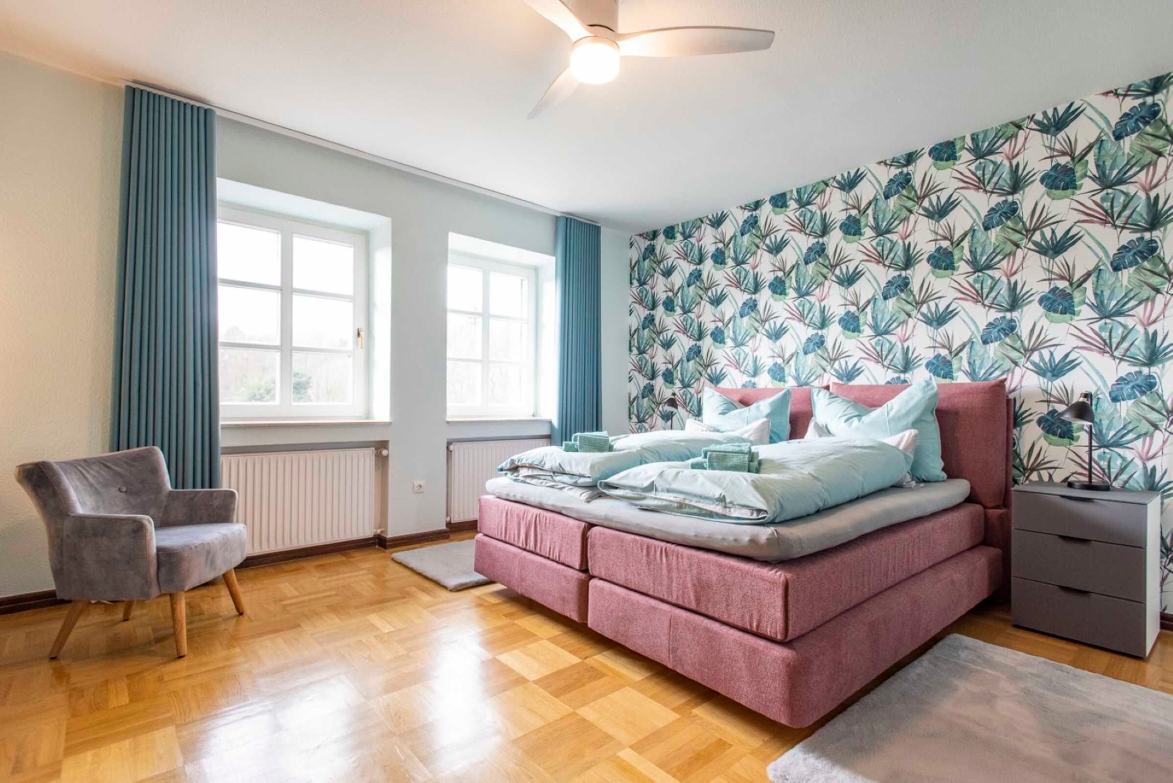Ein Schlafzimmer mit Bett, Stuhl, Nachttisch und Fenster.