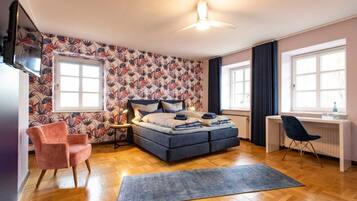 Ein Schlafzimmer mit einem Bett, einem Schreibtisch, einem Stuhl, einem Fernseher und einer Wand mit Muster.