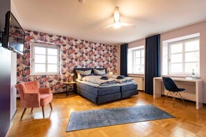 A bedroom with a bed, a desk, a chair, a TV, and a patterned wall. - Herrenhaus im Artland - Herrenhaus (Ankum)