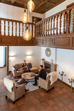 A spacious living room with a high ceiling, wooden balustrade, and a fireplace. - Herrenhaus im Artland - Herrenhaus (Ankum)