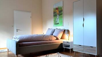 Une chambre à coucher avec un lit, une table de chevet, une lampe, une armoire et un tableau au mur.