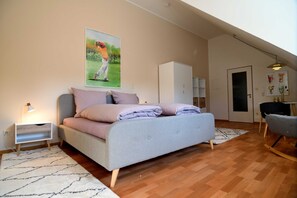A bedroom with a bed, a nightstand, a lamp, a painting, a wardrobe, and a door. - Appartement Crows Nest - Crow´s Nest (Ankum)
