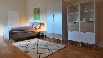 Un dormitorio con cama, mesita de noche, armario y alfombra.