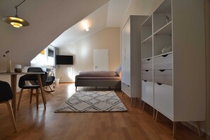 Et moderne loftværelse med skråvæg, seng, skrivebord og garderobeskab.