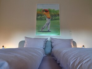 Una camera da letto con un letto, due cuscini e un quadro raffigurante un golfista.