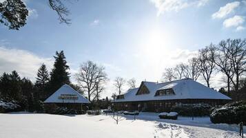 Eine Lodge mit schneebedecktem Dach, umgeben von Bäumen und blauem Himmel.