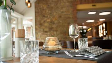Un ambiente de restaurante con una mesa lista para comer, que incluye una vela, una copa de vino y cubiertos.