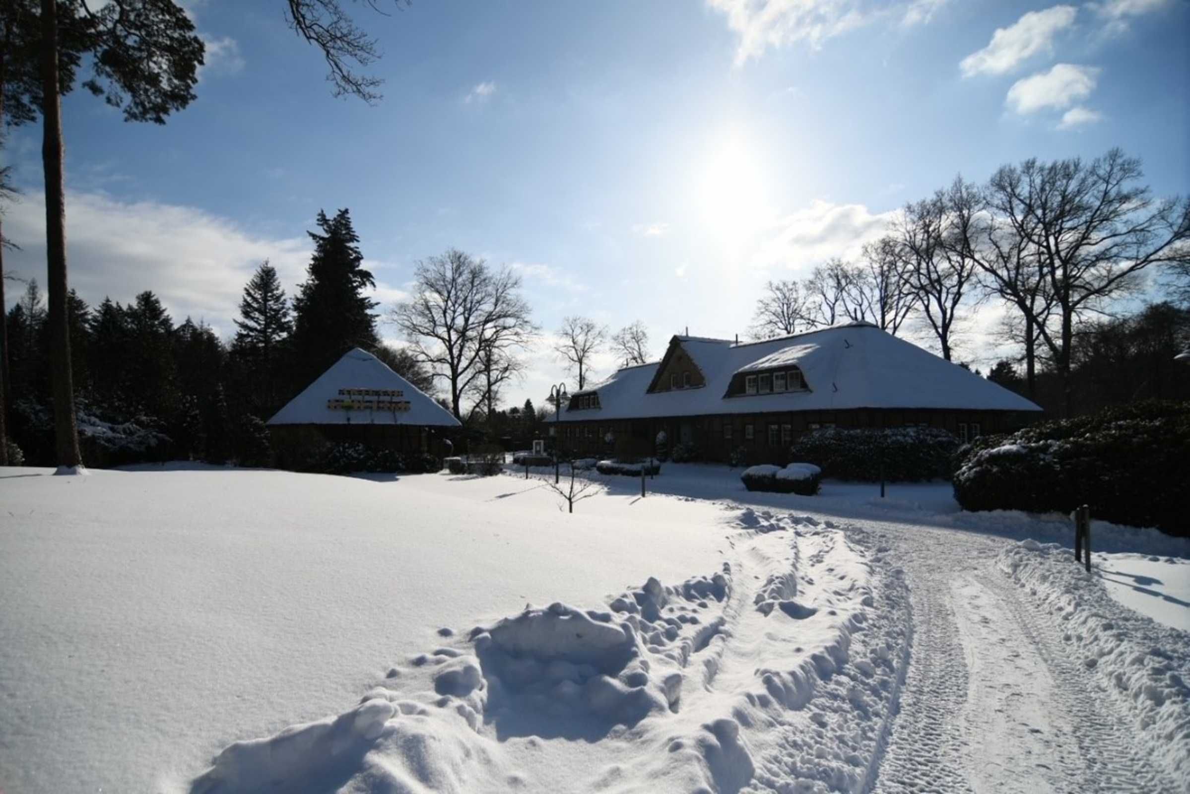 A snow-covered landscape with a building featuring a snow-covered roof and a clear sky.