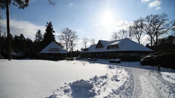 A snow-covered landscape with a building featuring a snow-covered roof and a clear sky.