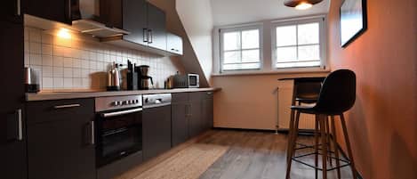 A modern kitchen with dark cabinetry, a built-in oven, and a window providing natural light.
