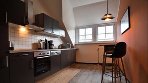 A modern kitchen with dark cabinetry, a built-in oven, and a window providing natural light.