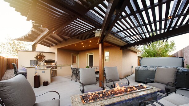 An outdoor patio with a fire feature, seating, and a grill area.