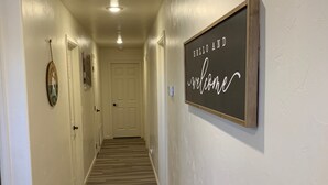 A hallway with a wooden floor, white walls, and a welcome sign.