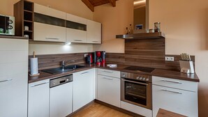 Une cuisine moderne avec des armoires blanches, un four encastré et un plan de travail en bois.