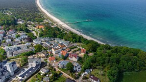 Vue aérienne d’une zone résidentielle côtière, avec des maisons, une plage et une jetée.