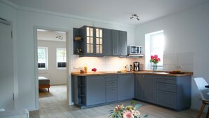 A modern kitchen with grey cabinets, a microwave, and a wooden countertop. There is a vase with flowers on the table.