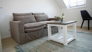 Ein Wohnzimmer mit einem braunen Sofa, einem weißen Couchtisch und einem schwarzen Sessel.
