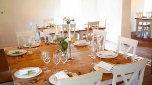 Ein Essbereich mit einem Holztisch, der für ein formelles Essen gedeckt ist, weißen Stühlen und einer Vase mit Blumen.