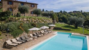 Un bâtiment en pierre avec une piscine et des chaises longues.