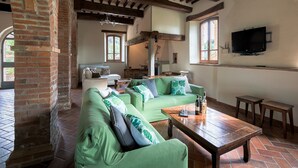 Un salon de style rustique avec des poutres apparentes, un canapé vert, une table basse en bois et un téléviseur fixé au mur.