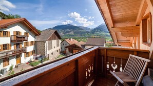 Un balcón de madera con vistas a un pueblo y montañas.