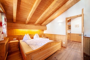 A wooden-paneled bedroom with a bed, nightstands, and a wooden ceiling.
