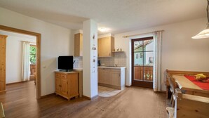 A spacious kitchen with wooden cabinets, a dining area with a table and benches, and a view through a glass door to an outdoor balcony. - Apartment "Hof am Schloss Edelweiss" with Mountain View and Wi-Fi (Prad am Stilfserjoch)