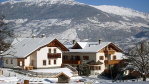 A chalet-style hotel with multiple buildings, a wooden fence, and a snowy mountain backdrop. - Apartment "Hof am Schloss Edelweiss" with Mountain View and Wi-Fi (Prad am Stilfserjoch)