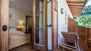A wooden-framed bedroom with a bed, a wooden chair, and a large window. - Apartment "Hof am Schloss Edelweiss" with Mountain View and Wi-Fi (Prad am Stilfserjoch)