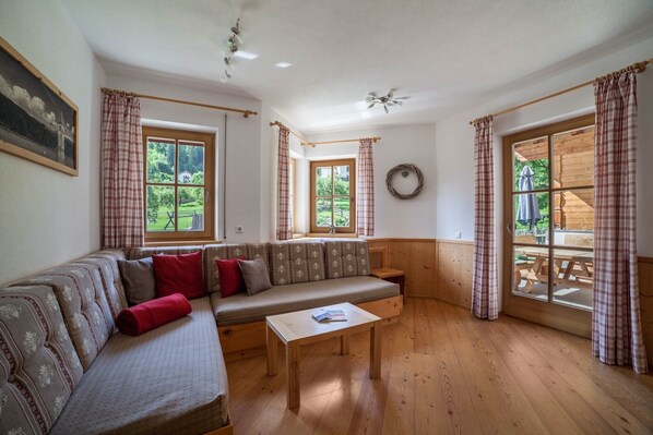 A cozy room with a sofa, a small table, and large windows with curtains.