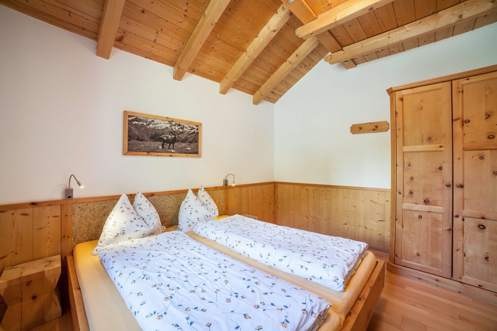 A wooden-paneled room with a bed, a wardrobe, and a framed picture on the wall.