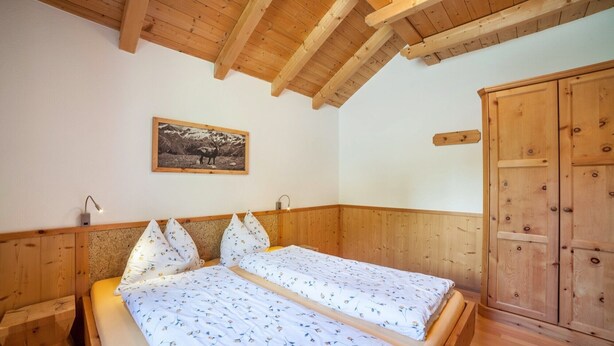 Una stanza con rivestimenti in legno, un letto, un armadio e un quadro appeso al muro.