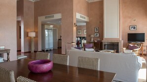 Ein geräumiges Wohnzimmer mit Kamin, Korbmöbeln und einem großen Fernseher.