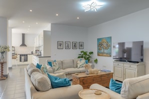 A modern living room with a sofa, coffee table, TV, and artwork on the wall.