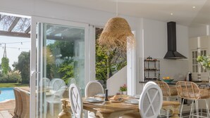 A modern kitchen with a large island, white chairs, and a dining table set for six. - Villa 'Buganvilla' with Mountain Views, Wi-Fi and Air Conditioning (Benalup Casas Viejas)