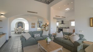 A spacious living area with two green sofas, a wooden coffee table, and a dining area in the background. - Villa 'Buganvilla' with Mountain Views, Wi-Fi and Air Conditioning (Benalup Casas Viejas)