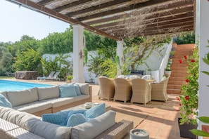 An outdoor patio with a pool, wicker furniture, and a pergola.