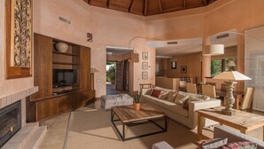 Amplia sala de estar con chimenea, televisor, sofá y una mesa de centro.