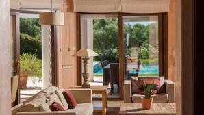 Sala de estar con sofá, una mesa, lámpara y vistas a una piscina y jardín.