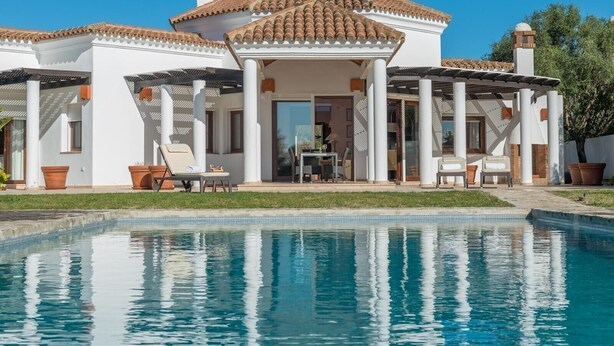 Una casa moderna con piscina, fachada blanca y tejado de tejas.